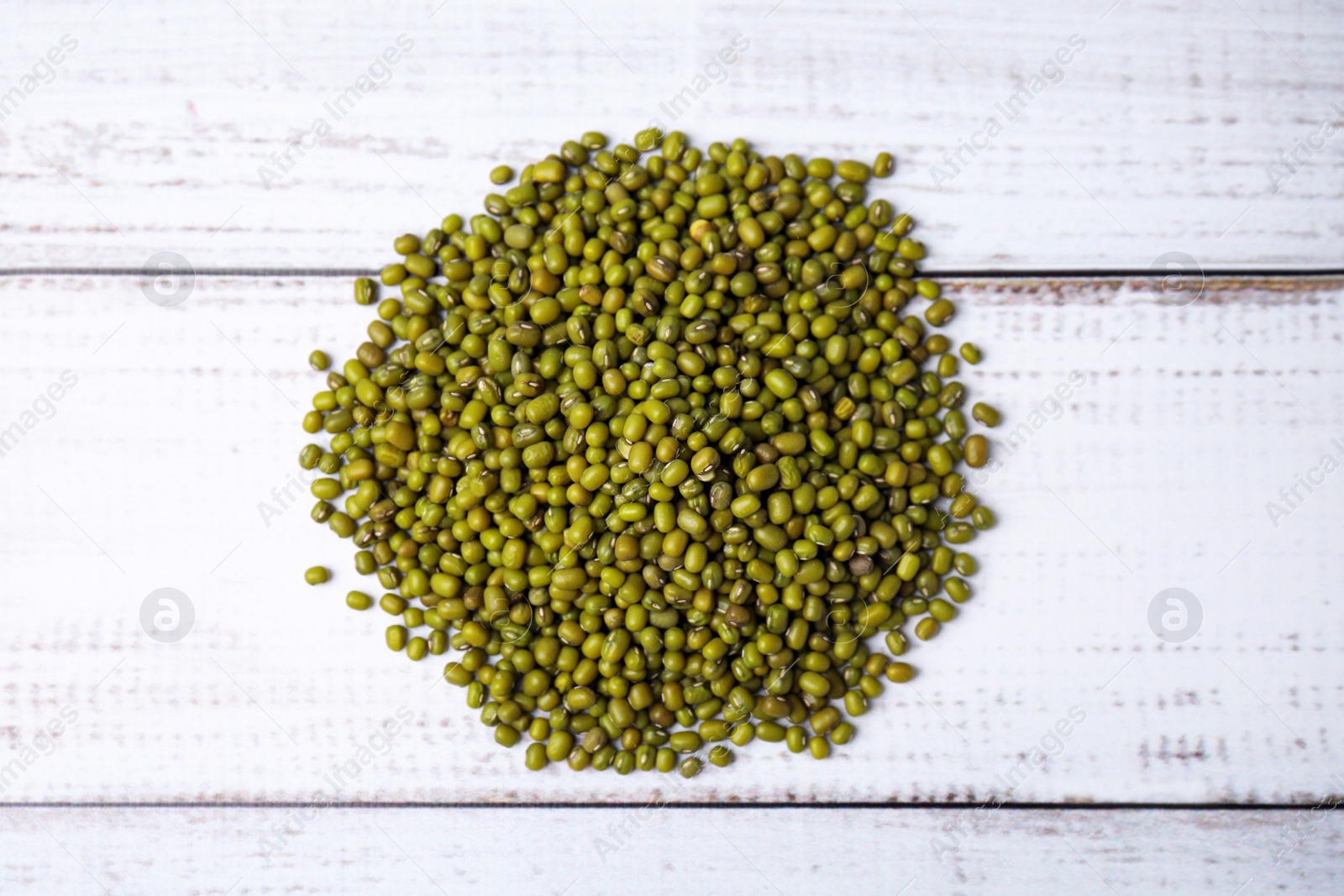 Photo of Pile of green mung beans on white wooden table, top view