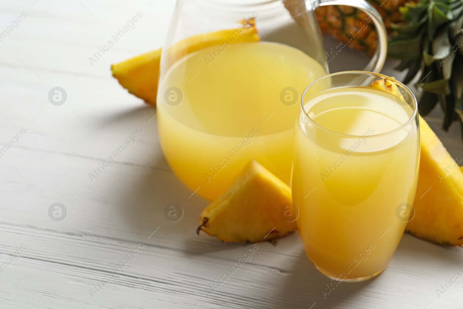 Photo of Delicious fresh pineapple juice on white wooden table, closeup