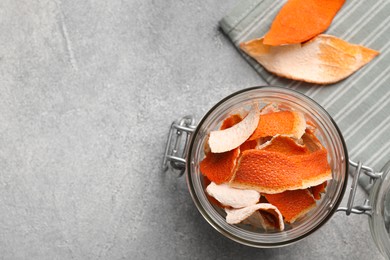 Photo of Glass jar with dry orange peels on light gray table, flat lay. Space for text