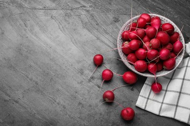 Photo of Bowl with fresh ripe radishes on grey table, flat lay. Space for text