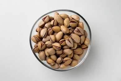 Photo of Bowl with pistachio nuts on white background, top view