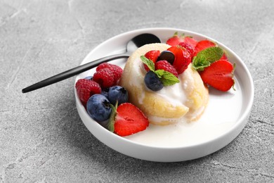 Photo of Delicious vanilla fondant served with fresh berries on grey textured table