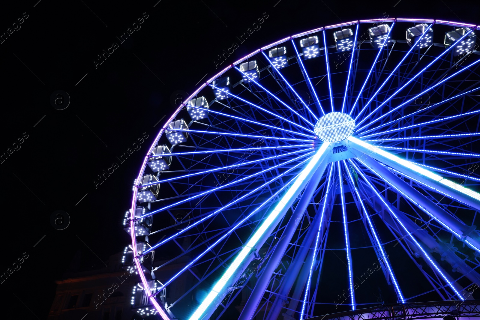 Photo of Beautiful glowing Ferris wheel against dark sky, low angle view