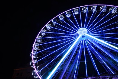 Beautiful glowing Ferris wheel against dark sky, low angle view