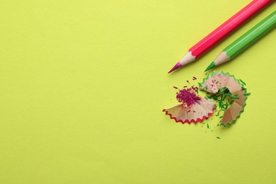 Photo of Pencils and shavings on light green background, flat lay. Space for text