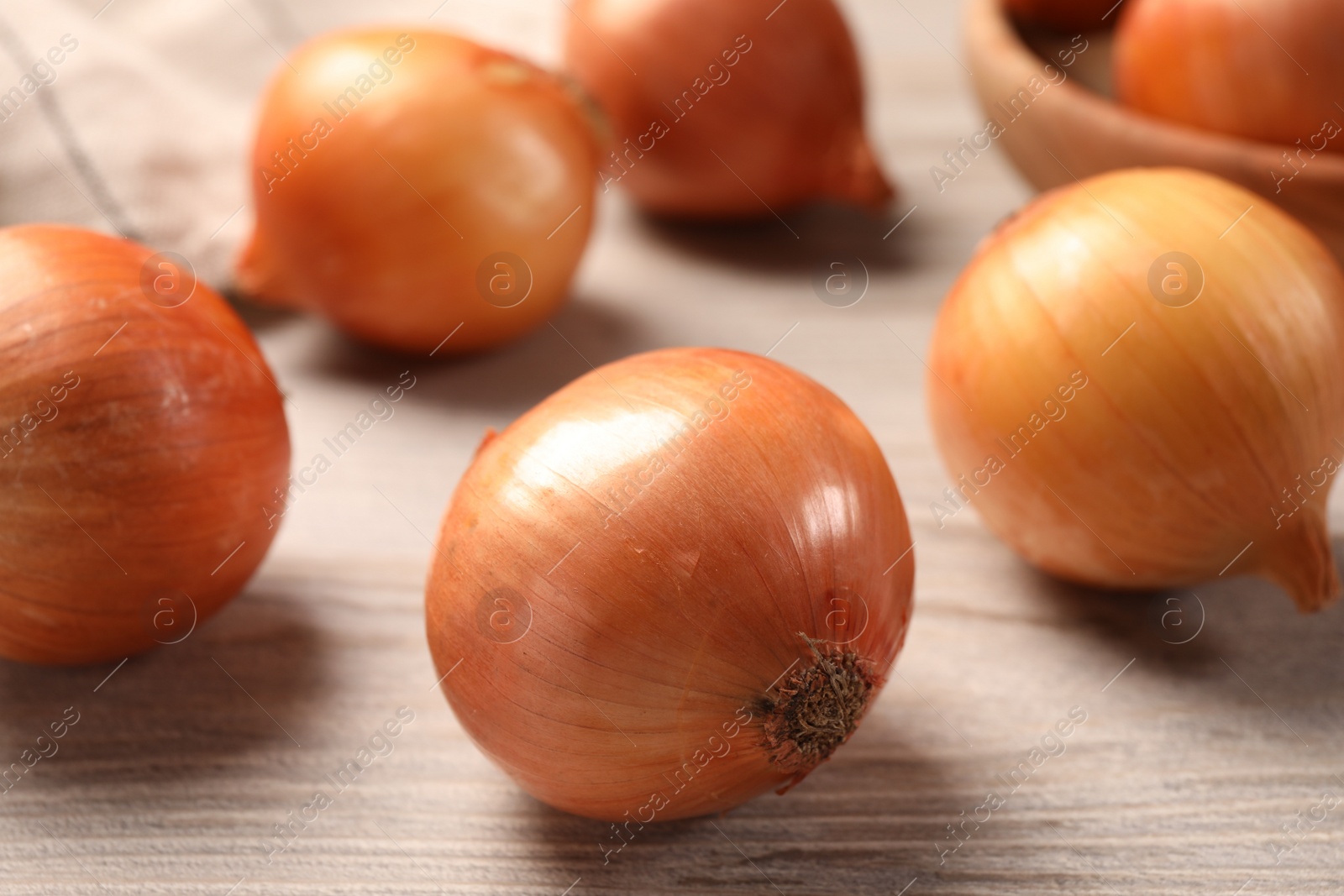 Photo of Many ripe onions on wooden table, closeup