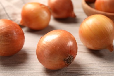 Photo of Many ripe onions on wooden table, closeup