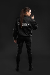 Photo of Female security guard using portable radio transmitter on dark background