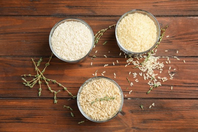 Photo of Glasses with different types of rice on wooden background, top view