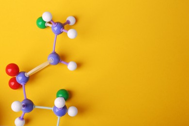 Photo of Structure of molecule on yellow background, top view and space for text. Chemical model