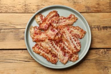 Delicious fried bacon slices on wooden table, top view