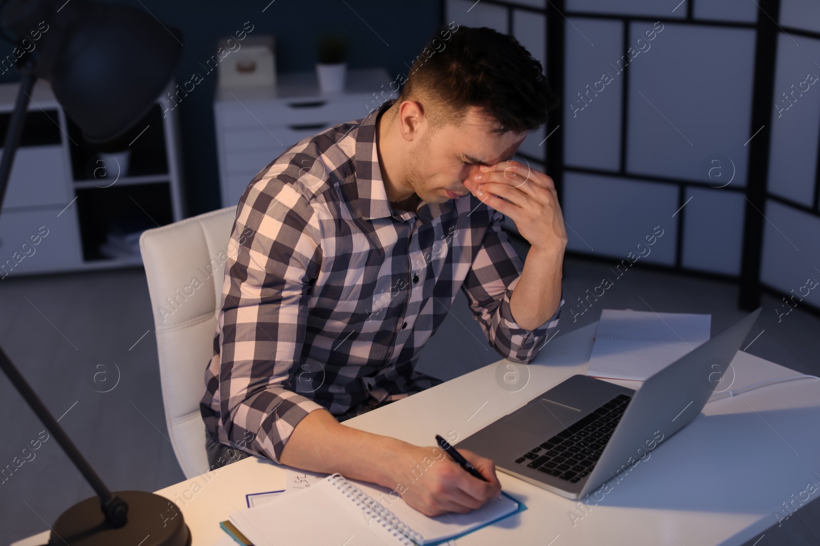 Photo of Overworked man with headache in office