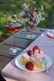 Photo of Glass of wine and cake on table served for romantic date in garden