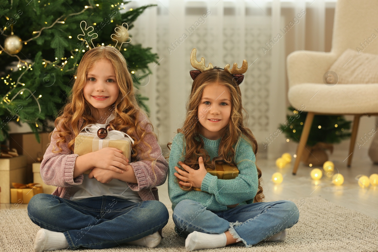 Photo of Cute little girls with Christmas gifts at home