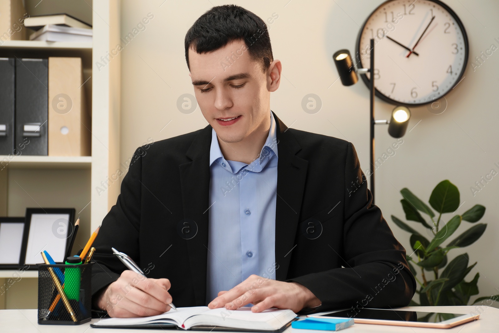 Photo of Man taking notes at table in office