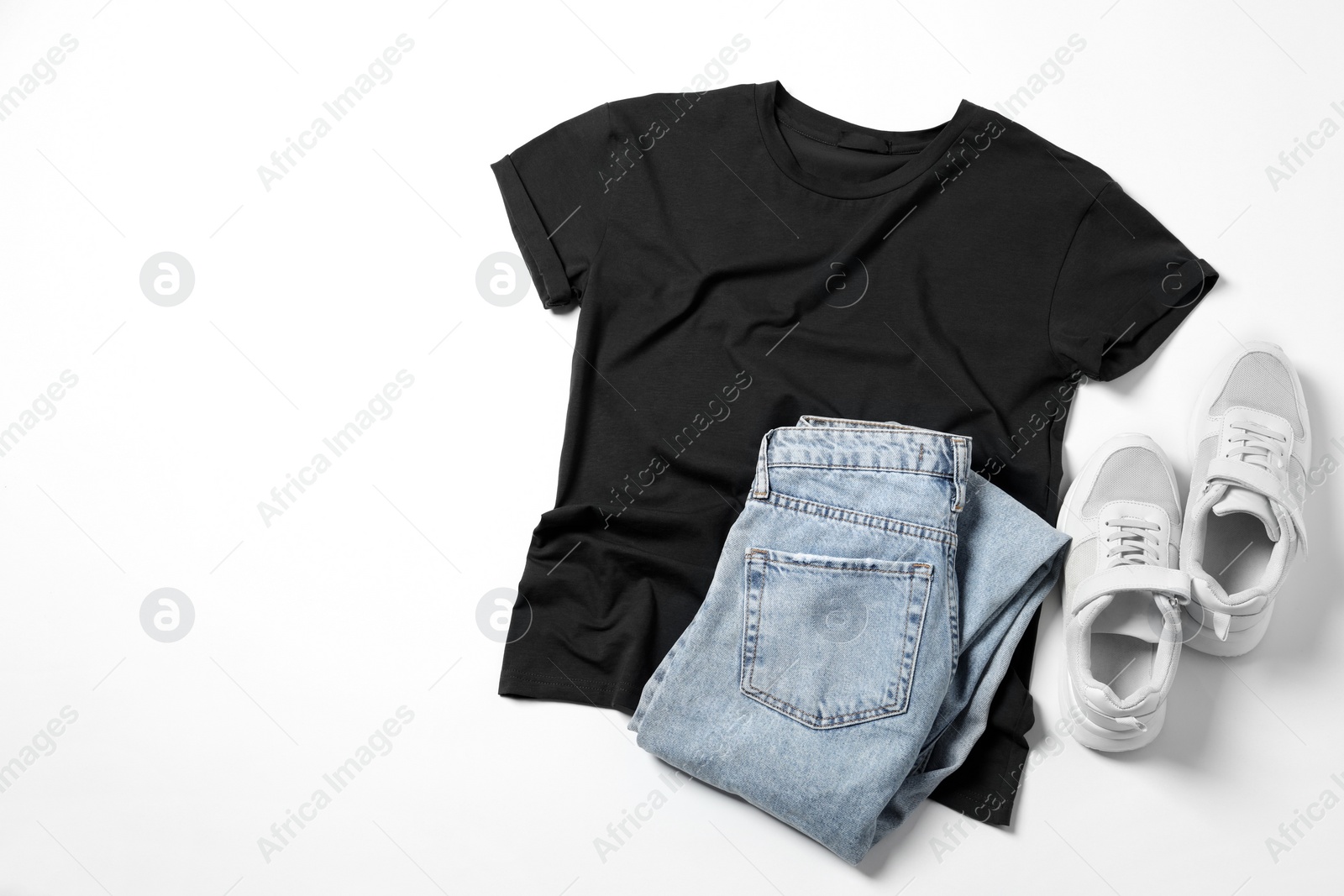 Photo of Stylish t-shirt, jeans and sneakers on white background, flat lay. Space for text