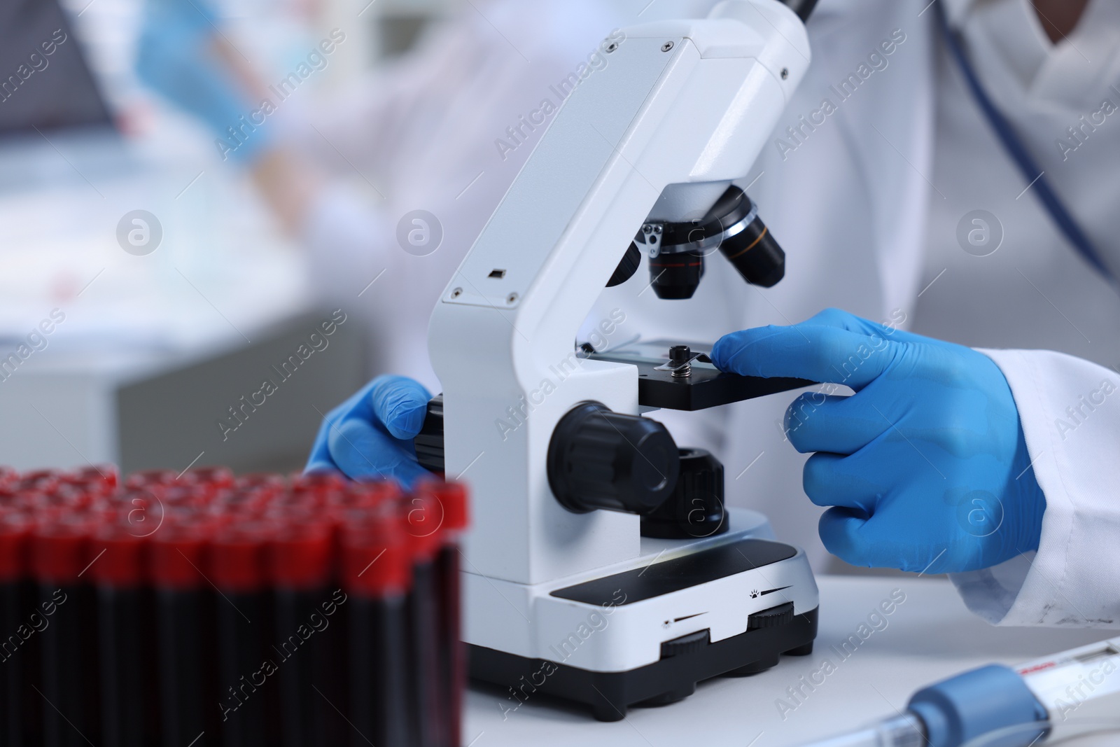 Photo of Scientist working with microscope in laboratory, closeup