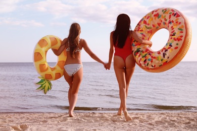 Young woman in bikini with girlfriend on beach. Lovely couple