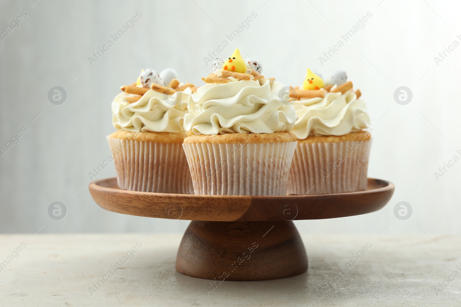 Photo of Tasty Easter cupcakes with vanilla cream on gray table