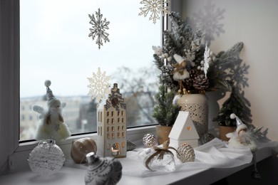 Photo of Many beautiful Christmas decorations and fir trees on window sill indoors