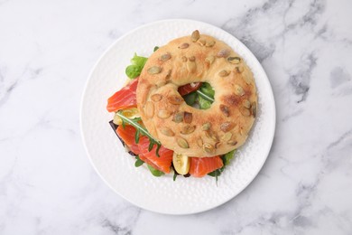 Tasty bagel with salmon and tomatoes on white marble table, top view