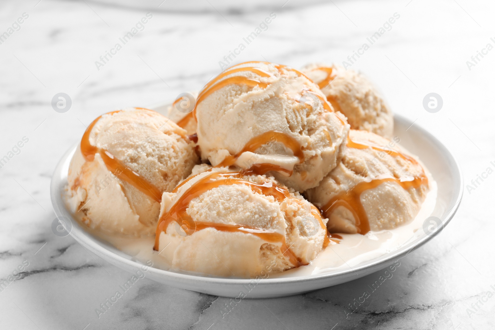 Photo of Tasty ice cream with caramel sauce on plate