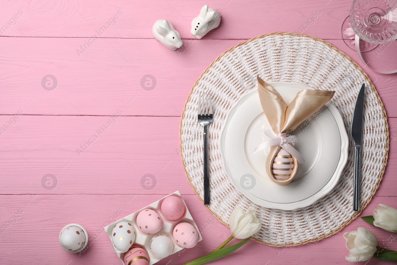 Photo of Festive table setting with painted eggs, plate and tulips, flat lay and space for text. Easter celebration