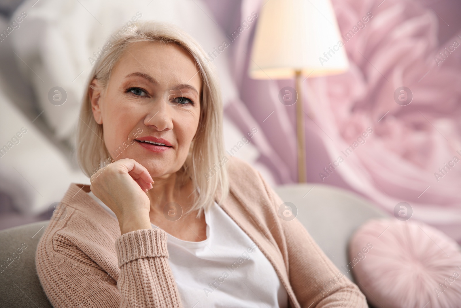 Photo of Beautiful mature woman on sofa at home. Space for text