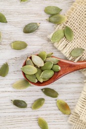 Photo of Spoon with peeled seeds on light wooden table, flat lay