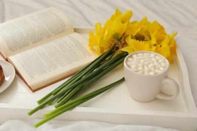 Photo of Bouquet of beautiful daffodils and hot drink on bed