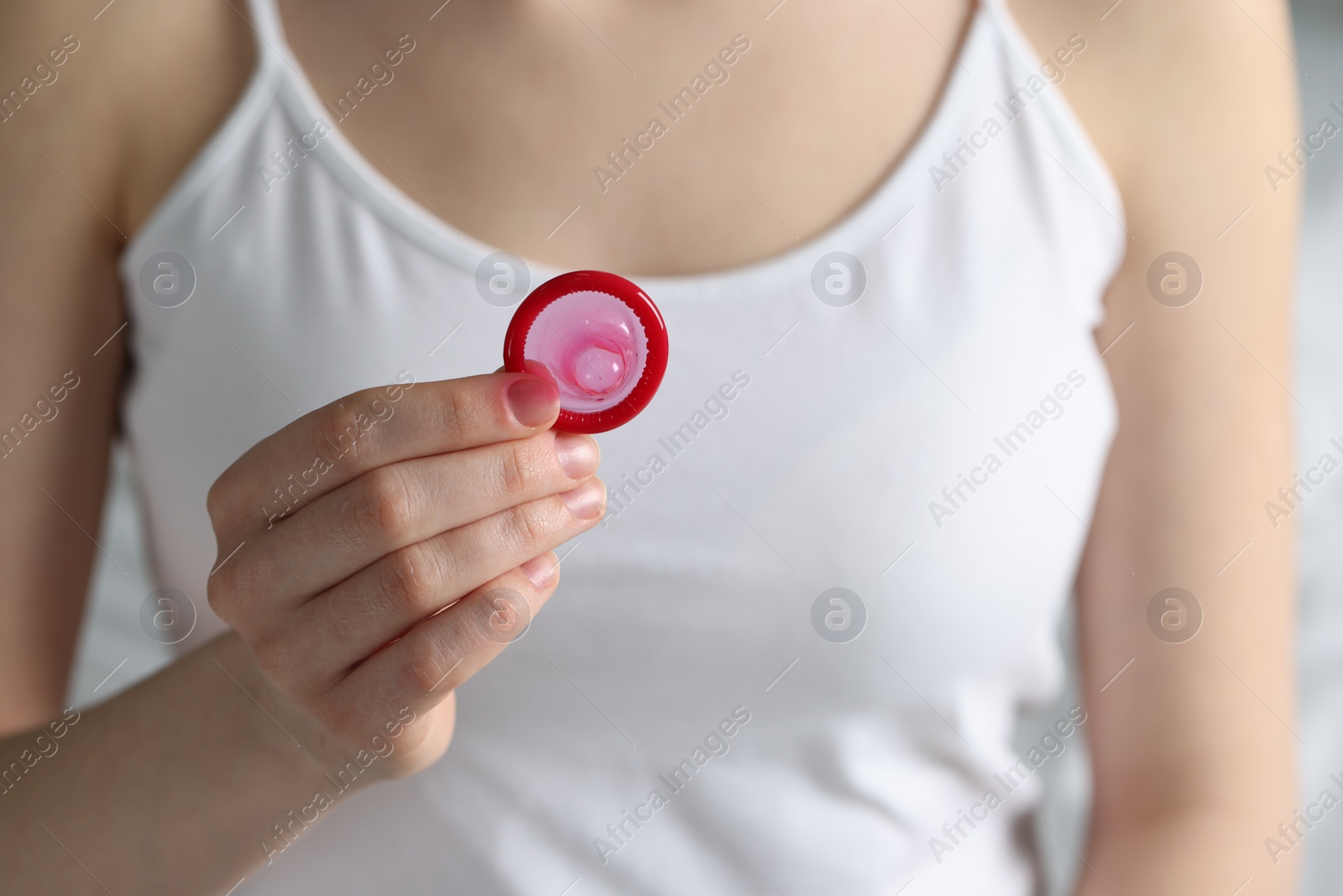 Photo of Woman holding unpacked condom, closeup. Safe sex