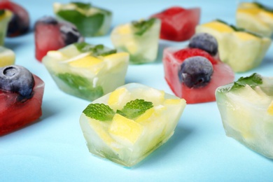 Fruit and berry ice cubes on color background