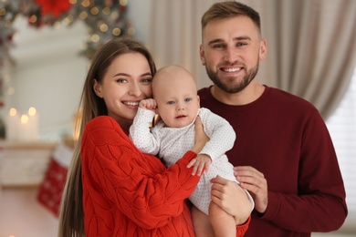 Photo of Family with cute baby in room decorated for Christmas holiday