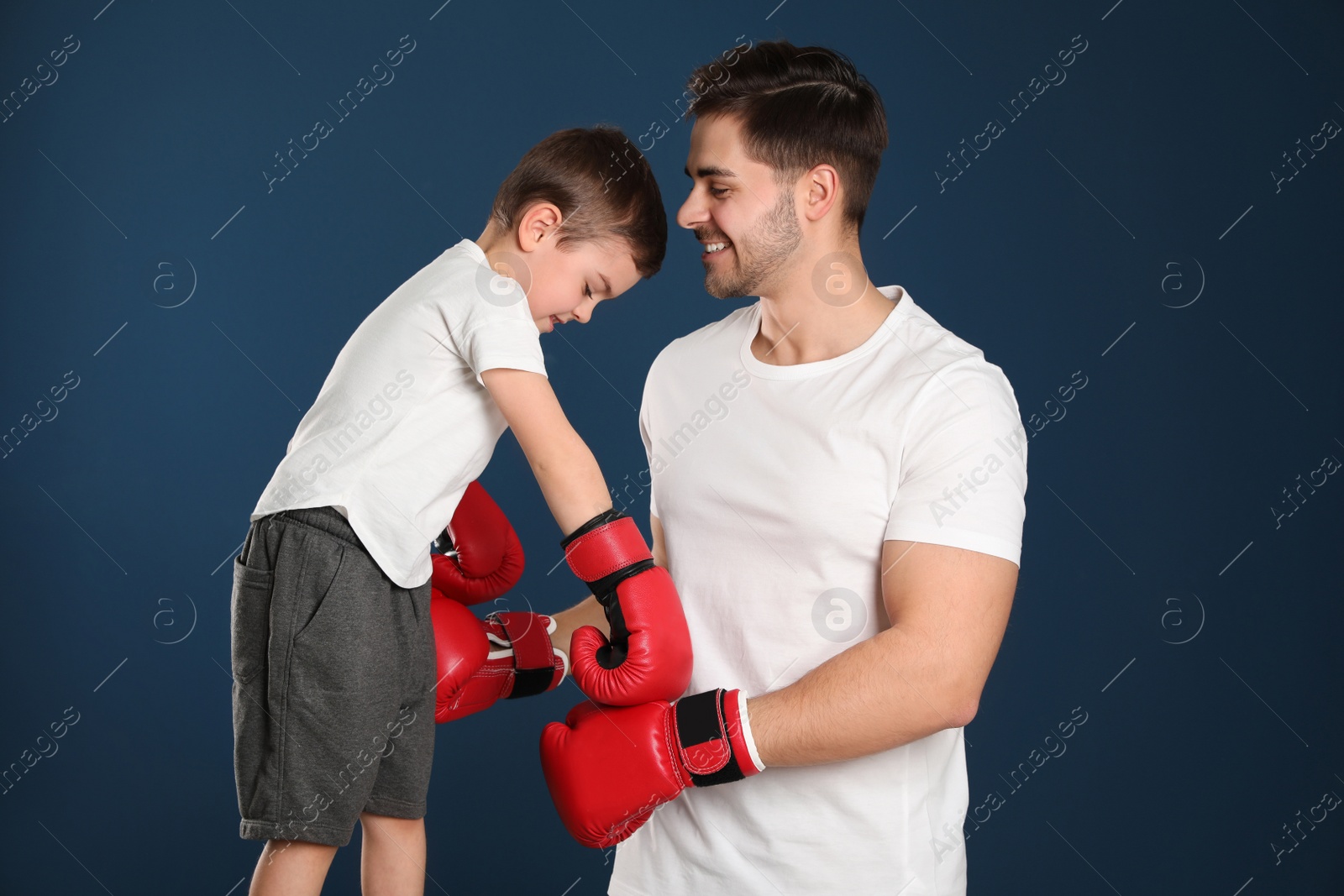 Photo of Dad and his son with boxing gloves on color background