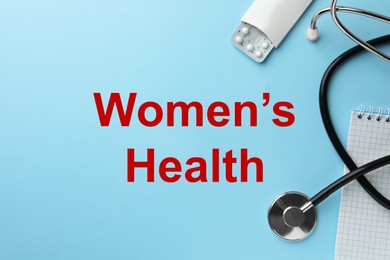 Photo of Words Women's Health, notebook, stethoscope and pills on light blue background, flat lay. Space for text