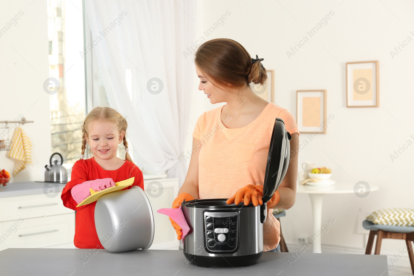 Photo of Mother and daughter cleaning modern multi cooker in kitchen