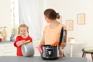 Mother and daughter cleaning modern multi cooker in kitchen