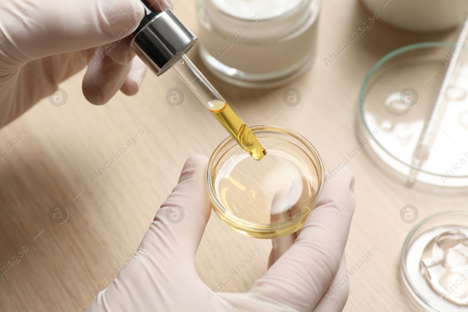 Photo of Scientist making cosmetic product at wooden table, closeup