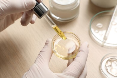 Scientist making cosmetic product at wooden table, closeup