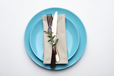 Photo of Stylish elegant cutlery with napkin and floral decor in plate on white background, top view
