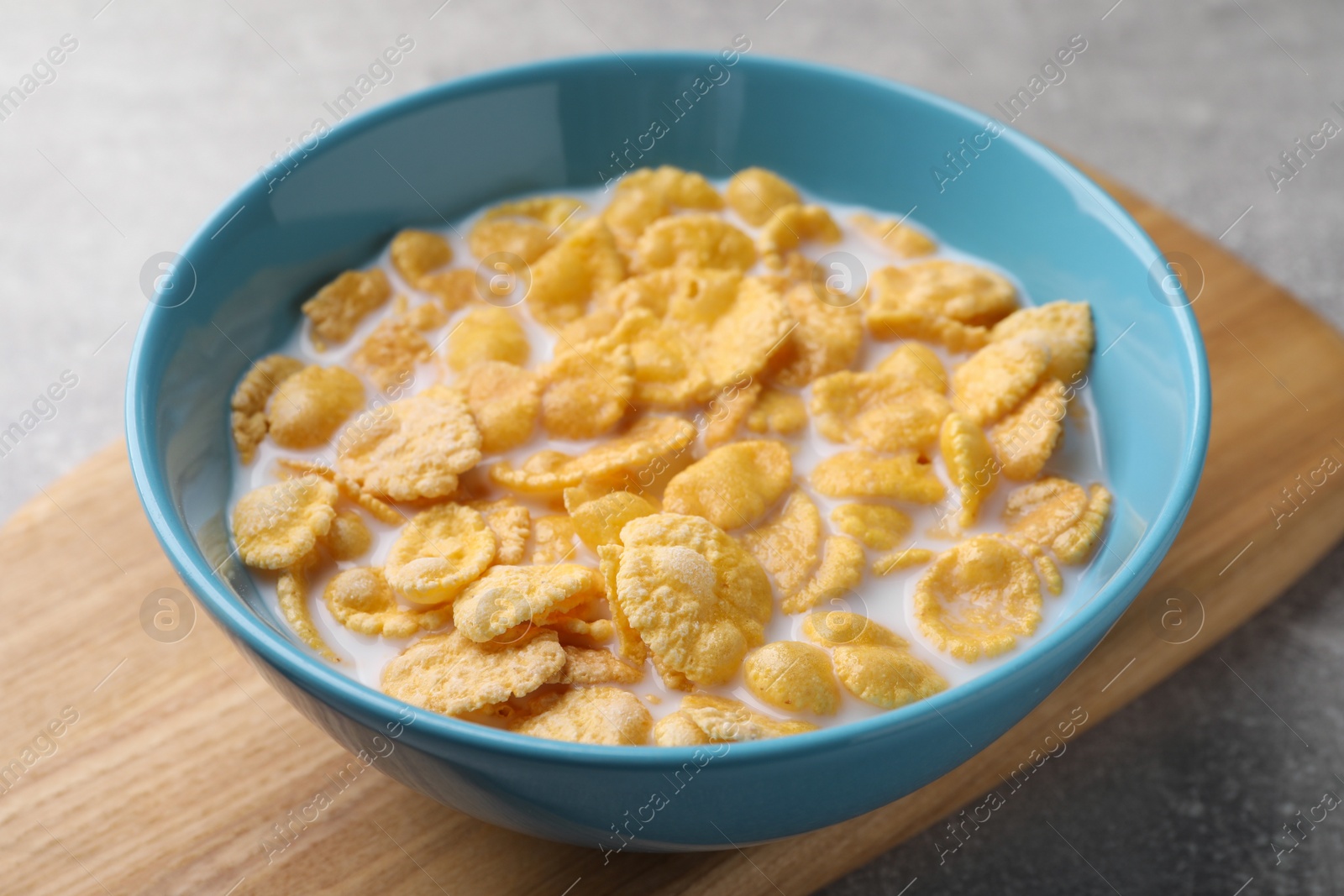 Photo of Tasty cornflakes with milk in bowl on table, closeup