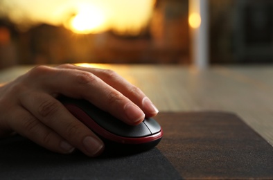 Woman using computer mouse at table, closeup. Space for text