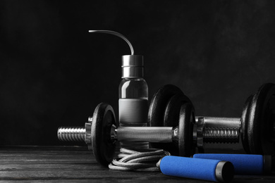 Photo of Gym equipment and accessories on wooden floor against dark background