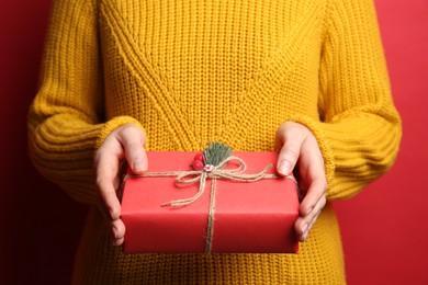 Photo of Woman holding Christmas gift box on red background, closeup