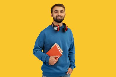 Photo of Student with headphones and books on yellow background