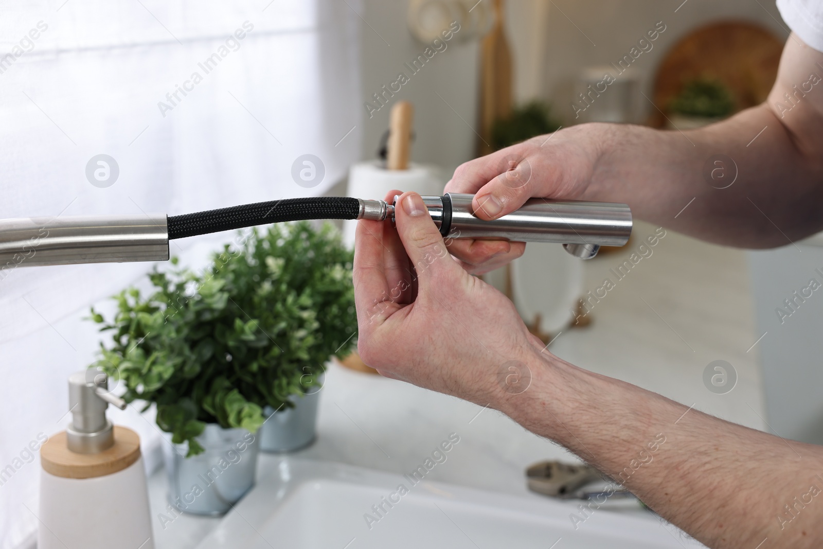 Photo of Plumber examining metal faucet at home, closeup