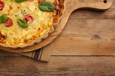 Photo of Delicious quiche with cheese, tomatoes and basil on wooden table, top view. Space for text