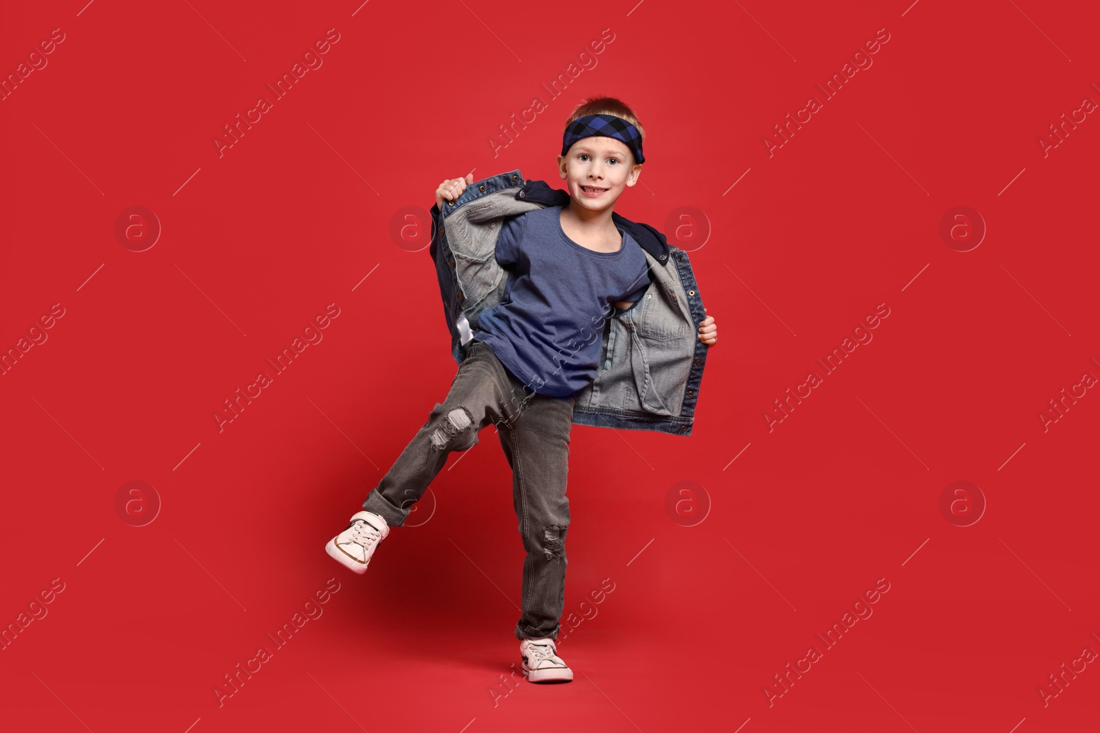 Photo of Happy little boy dancing on red background