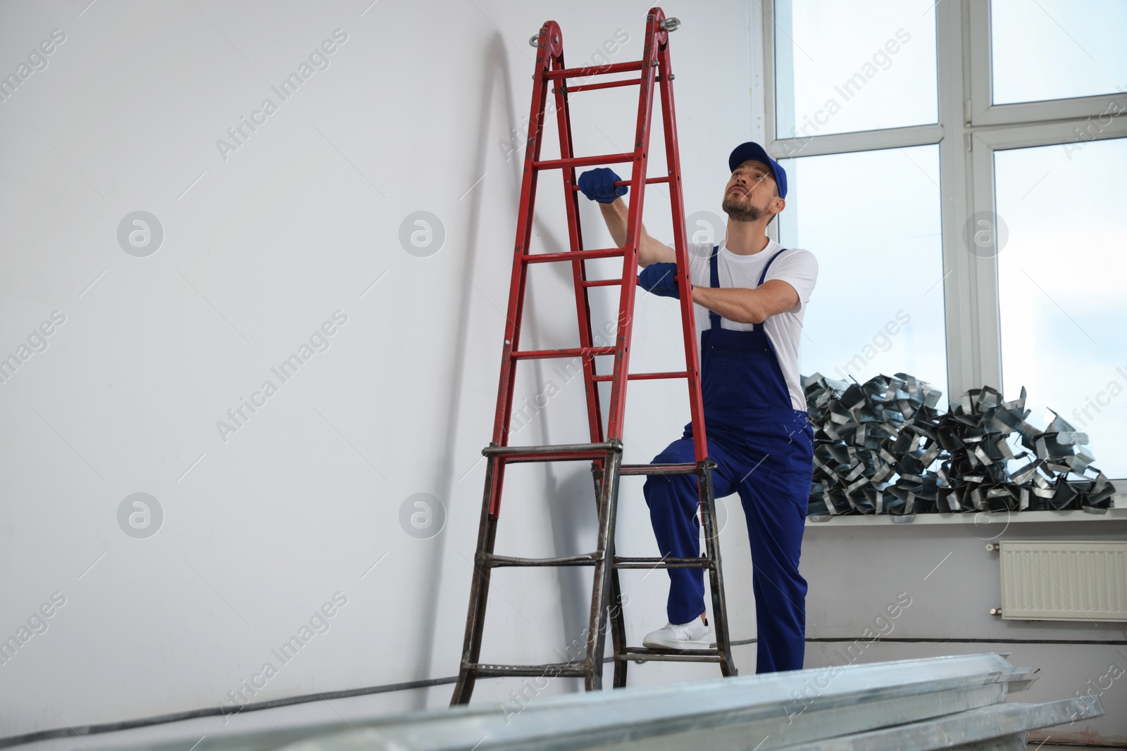 Photo of Construction worker climbing up stepladder in room prepared for renovation