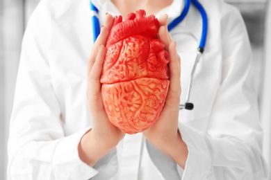 Photo of Doctor holding model of heart, closeup. Heart attack concept